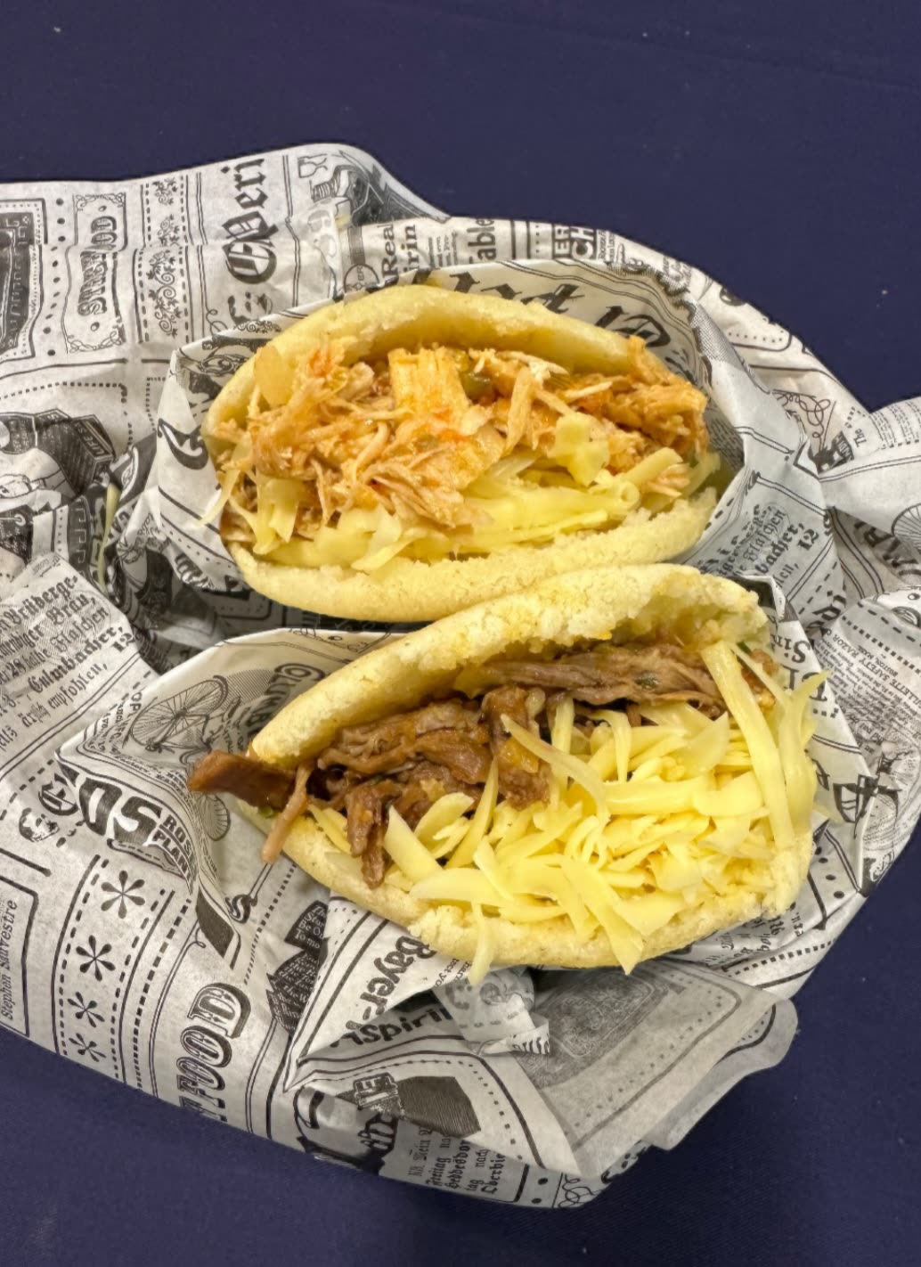 Dos arepas rellenas de pollo esmechado y carne mechada con queso